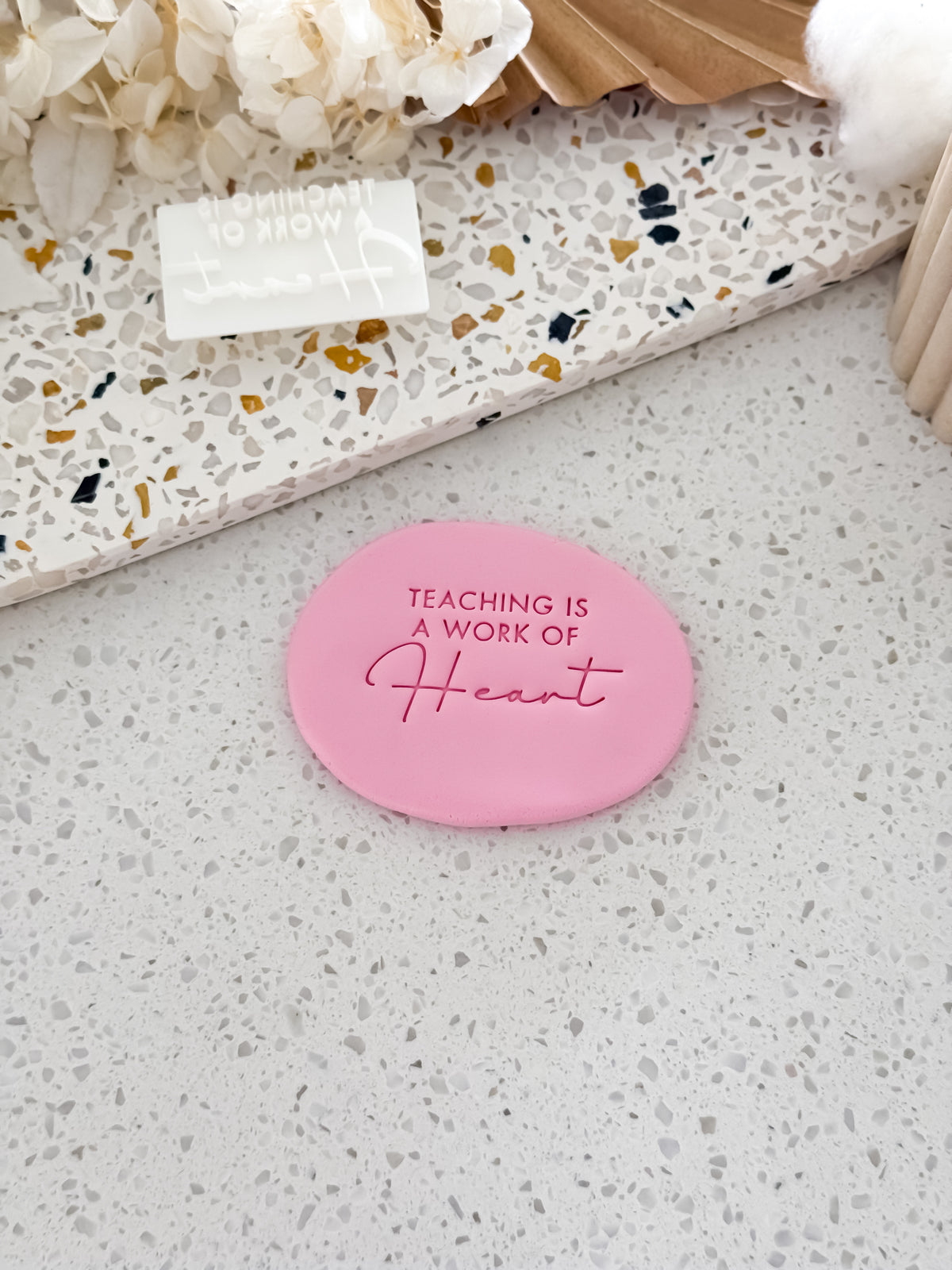 Teaching Is a Work of Heart teacher cookie stamp by O'Khach, shown stamped in pink fondant